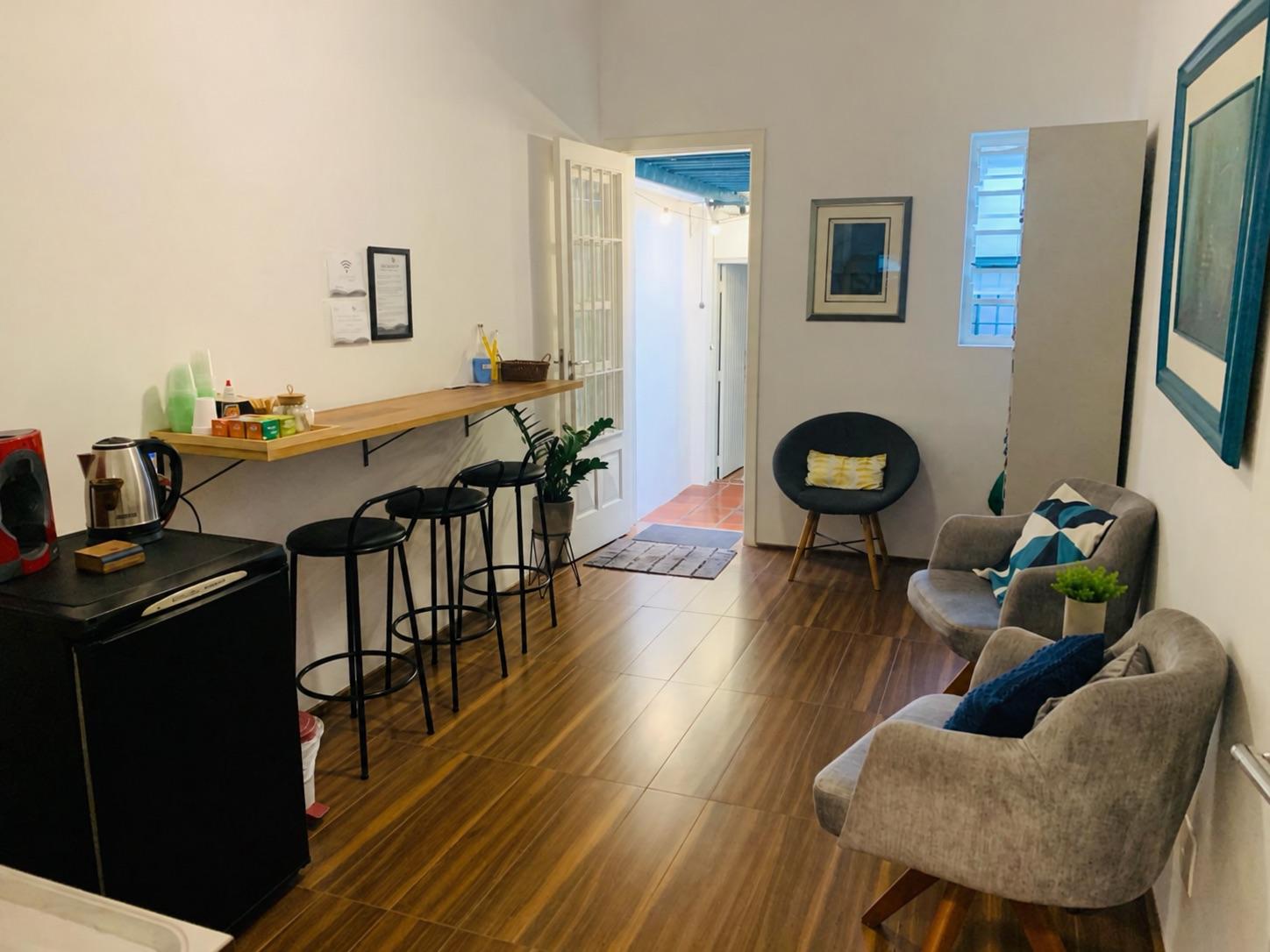 Sala de espera dos profissionais com bancada, banquetas, chaleira e poltronas cinza