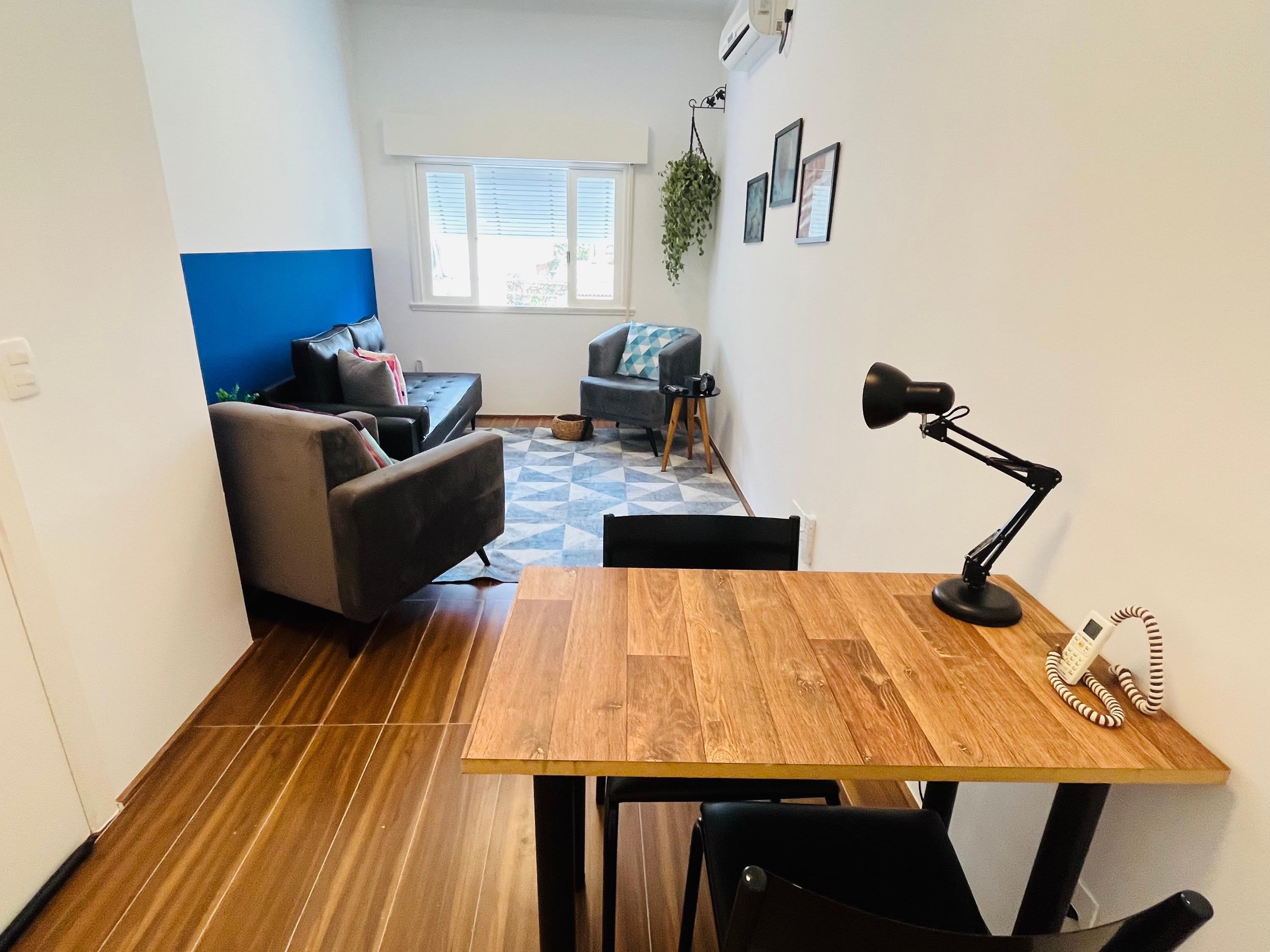 Sala 4 vista da escrivaninha, com divã, poltronas e janela ao fundo