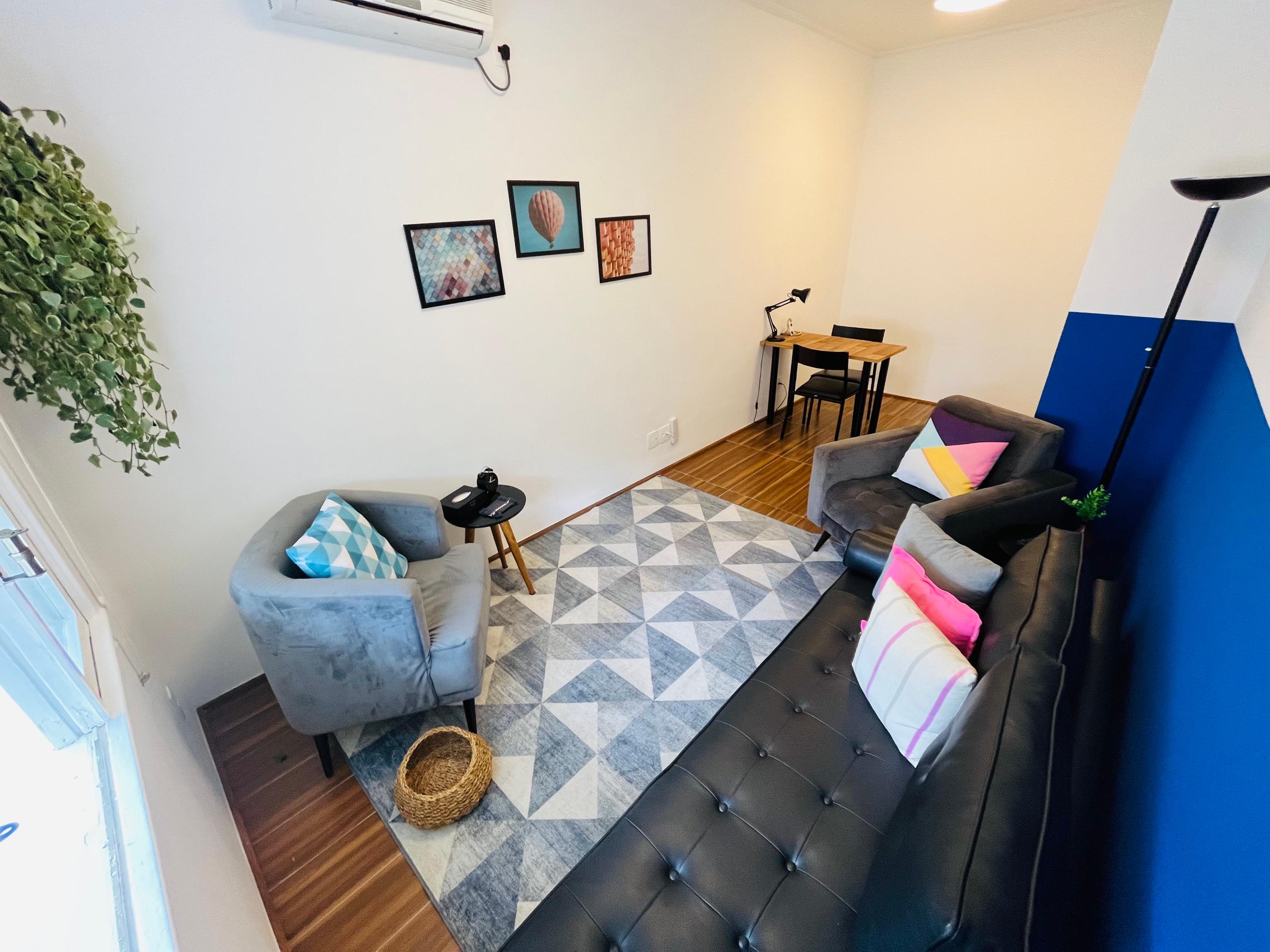 Sala 4 com poltronas, tapete geométrico e quadros na parede